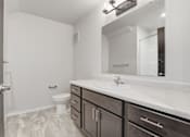 Thumbnail 36 of 68 - A bathroom with a toilet, sink, and mirror.
