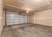 Thumbnail 42 of 64 - A large, empty garage with a concrete floor and white walls.