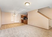 Thumbnail 10 of 64 - A spacious living room with a carpeted floor and a staircase on the right side.