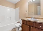 Thumbnail 45 of 64 - A bathroom with a white toilet, sink, and bathtub.
