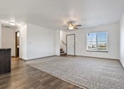 Thumbnail 3 of 47 - A spacious room with a ceiling fan and a large rug on the floor.