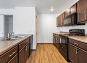 Thumbnail 30 of 44 - A kitchen with dark wood cabinets and a black stove top oven.