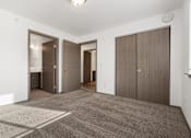Thumbnail 44 of 59 - A room with a carpeted floor and three doors.