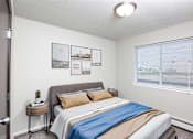 Thumbnail 3 of 18 - A bedroom with a bed, pillows, a small table, and pictures on the wall.