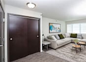 Thumbnail 2 of 18 - A living room with a couch, a coffee table, and a painting on the wall.