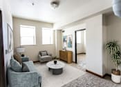 Thumbnail 3 of 31 - A living room with a grey couch, a white coffee table, and a plant.