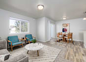 Thumbnail 11 of 22 - A living room with a grey couch, a white coffee table, and a rug with a pattern.