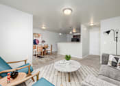 Thumbnail 6 of 22 - A living room with a grey couch and a white coffee table.
