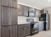 Thumbnail 44 of 68 - A kitchen with dark brown cabinets and stainless steel appliances.
