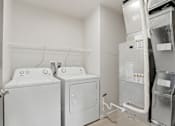 Thumbnail 62 of 68 - A white washing machine and dryer in a small laundry room.
