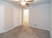 Thumbnail 16 of 17 - A room with a ceiling fan and carpeted floor.