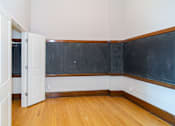 Thumbnail 1 of 9 - A room with a blackboard on the wall and a wooden floor.