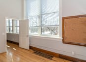 Thumbnail 4 of 9 - A room with a white door, a window with blinds, and a corkboard on the wall.