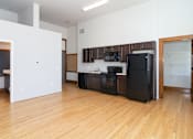 Thumbnail 9 of 9 - A kitchen with black appliances and wooden floors.