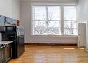 Thumbnail 6 of 9 - A kitchen with black appliances and wooden floors.