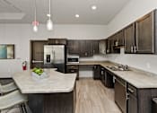 Thumbnail 17 of 37 - A kitchen with a marble countertop and dark wood cabinets.