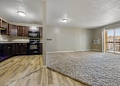 Thumbnail 4 of 41 - A large open living space with a kitchen area to the left and a doorway to another room to the right.