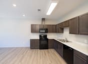Thumbnail 22 of 32 - A kitchen with brown cabinets and a black oven.