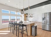 Thumbnail 60 of 68 - A modern kitchen with a bar area and a refrigerator.