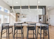 Thumbnail 40 of 68 - A kitchen with a white tile backsplash and a bar area with four chairs.