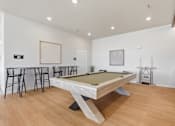 Thumbnail 67 of 68 - A pool table is in the middle of a room with a bar and chairs.