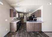 Thumbnail 34 of 81 - A kitchen with wooden floors and a black refrigerator.