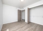 Thumbnail 9 of 16 - A room with a wooden floor and a white wall with a door and a closet.