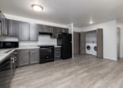Thumbnail 7 of 16 - A kitchen with black appliances and wooden floors.
