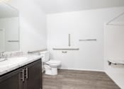 Thumbnail 15 of 16 - A white bathroom with a toilet, sink, and a bench.