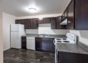 Thumbnail 4 of 15 - an empty kitchen with dark wood cabinets and white appliances