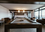 Thumbnail 20 of 41 - A pool table is in the middle of a room with a couch and a chair.