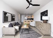 Thumbnail 19 of 42 - A living room with a grey couch and a black ceiling fan.