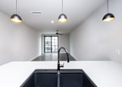 Thumbnail 17 of 41 - A modern kitchen with a black sink and pendant lights.