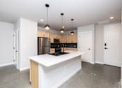 Thumbnail 9 of 41 - A kitchen with a white island and wooden cabinets.