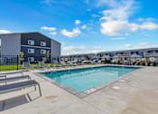 Thumbnail 49 of 58 - A swimming pool surrounded by lounge chairs in front of a building.