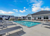 Thumbnail 8 of 58 - A swimming pool surrounded by sun loungers and a building in the background.