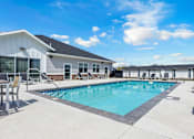 Thumbnail 50 of 58 - A swimming pool is surrounded by a concrete patio and a white building.