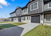 Thumbnail 9 of 43 - A modern two-story house with a grey exterior and a black garage door.