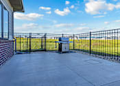 Thumbnail 25 of 59 - A black metal fence surrounds a concrete patio with a trash can in the middle.