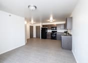 Thumbnail 12 of 19 - an empty living room and kitchen with black appliances and white walls