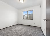 Thumbnail 16 of 31 - A room with a carpeted floor and a window showing a building outside.