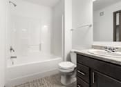 Thumbnail 25 of 31 - A white toilet sits next to a white bathtub in a bathroom.