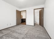 Thumbnail 5 of 31 - A carpeted room with a white wall and a brown door.