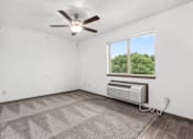 Thumbnail 17 of 31 - A room with a ceiling fan and a window with an air conditioner unit under it.