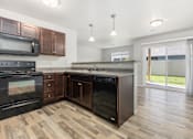 Thumbnail 3 of 26 - A kitchen with dark wood cabinets and black appliances.