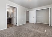Thumbnail 7 of 26 - A carpeted room with a closet and a doorway leading to a kitchen.