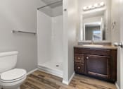 Thumbnail 9 of 26 - A white toilet sits next to a walk-in shower in a bathroom.