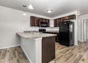 Thumbnail 12 of 26 - A kitchen with a black refrigerator and wooden cabinets.