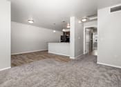 Thumbnail 19 of 26 - A spacious living room with a grey carpet and white walls.