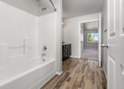 Thumbnail 21 of 26 - A white bathroom with a wooden floor and a white tub.